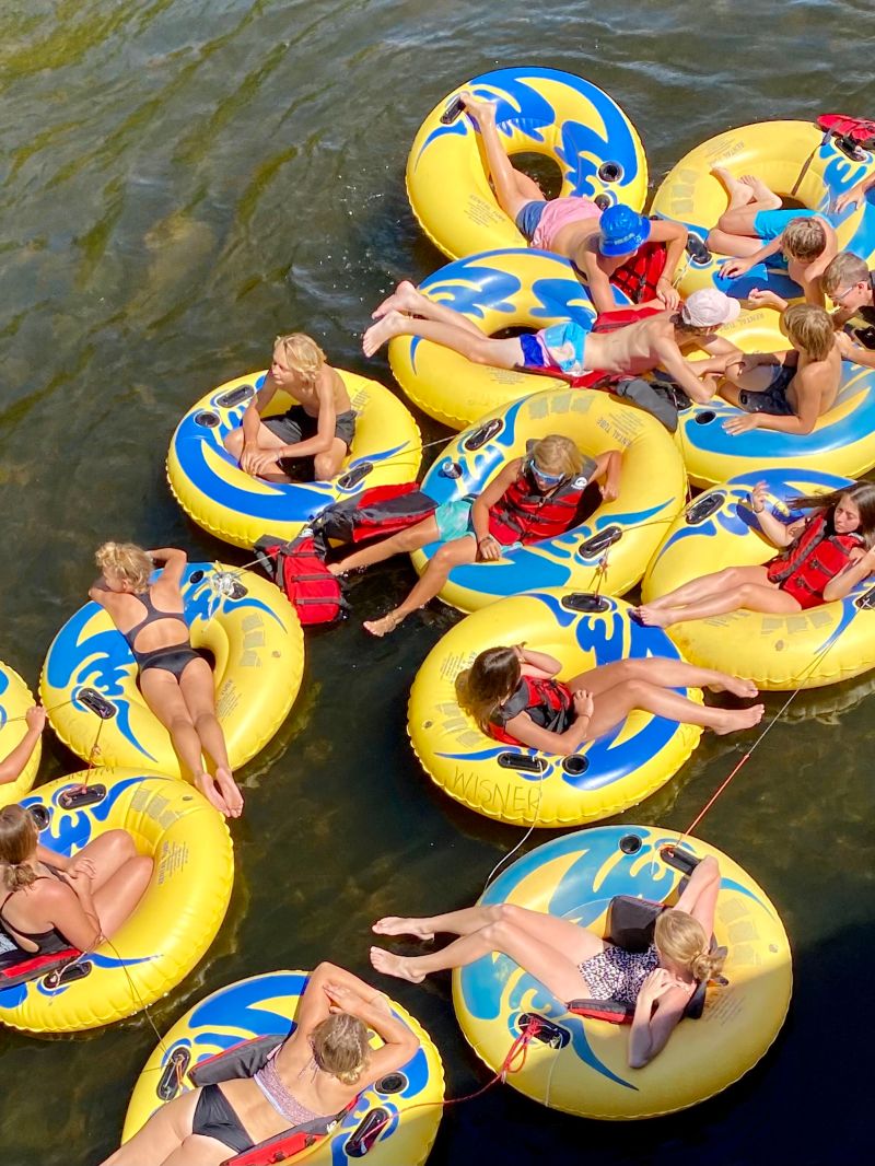 People relaxing in yellow inflatable tubes on a river, viewed from above.