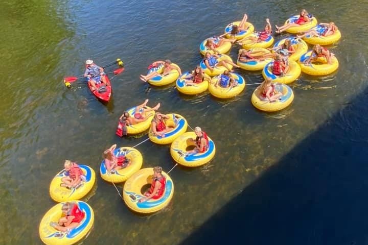People floating on yellow tubes and a kayak in a river.