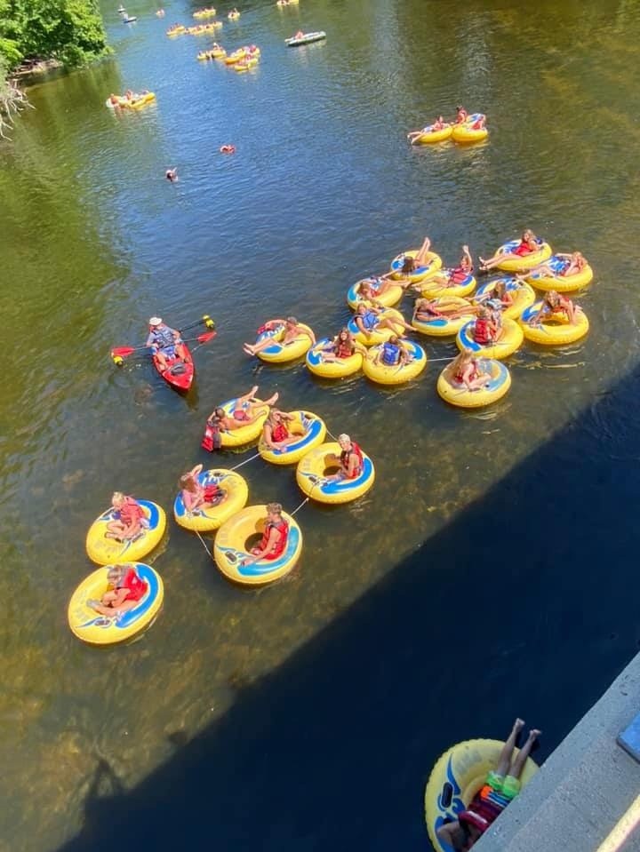 People floating on yellow tubes and a kayak in a river.
